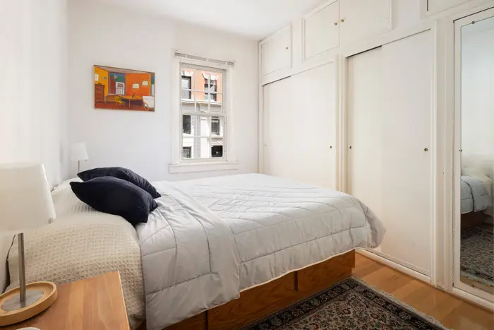 A view through the ornate gate into Pomander Walk NYC, showing charming Tudor-style buildings and a cobblestone path.